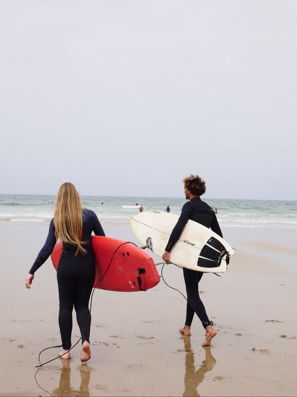 Two surfers walking into the water with their boards