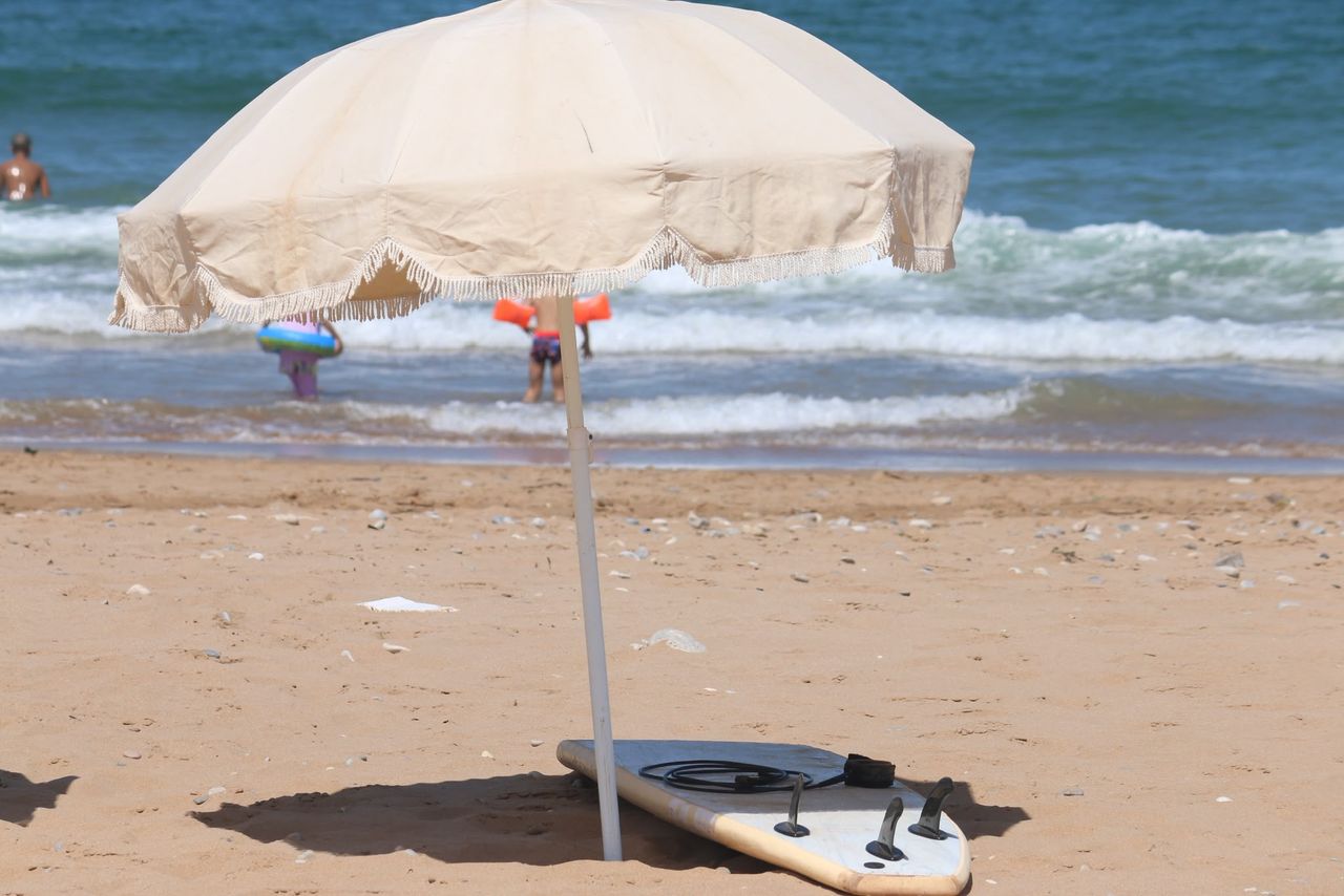 Parasol and board on the sand