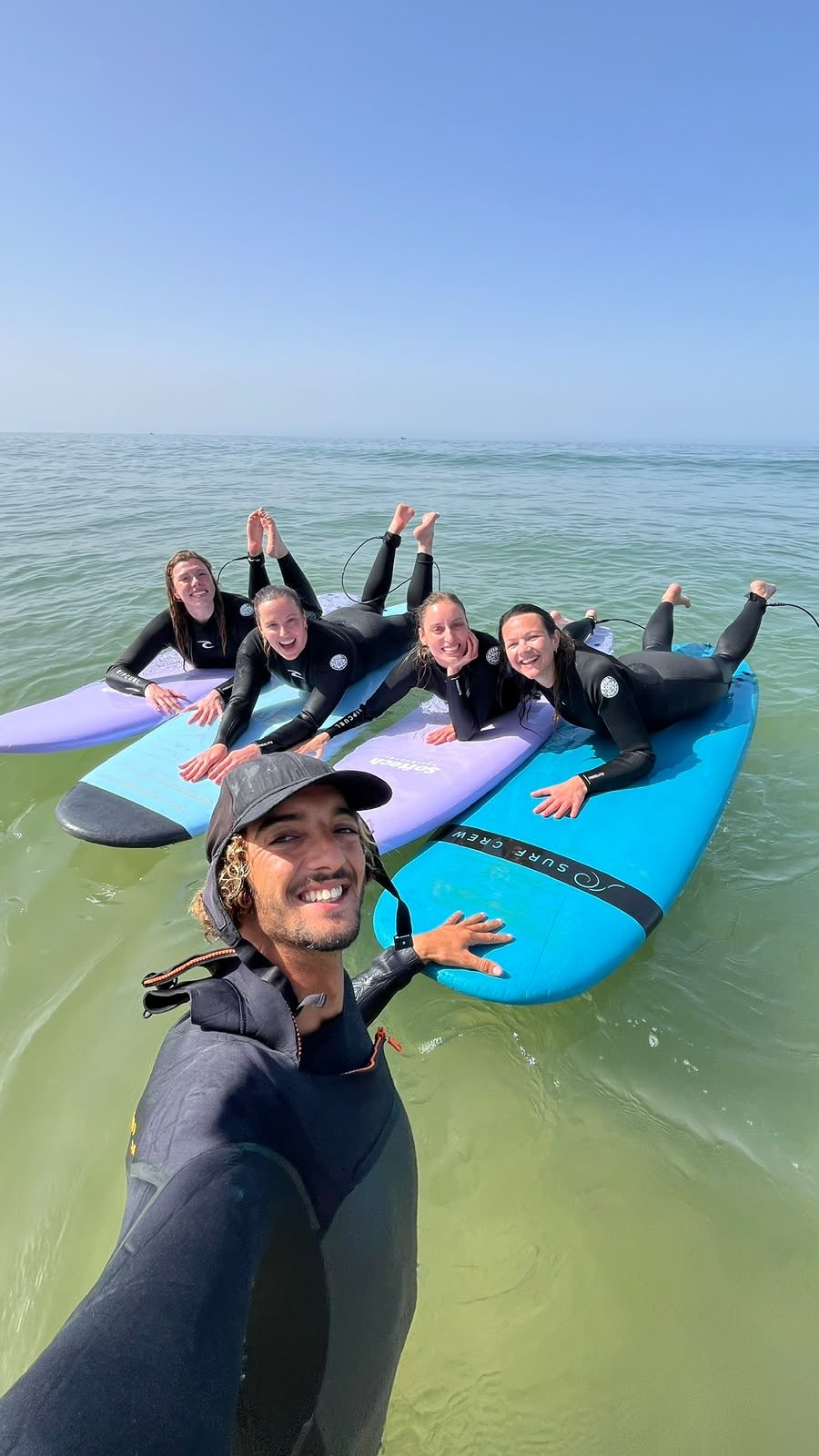 Coach Youness and four students lying on their boards in the lineup