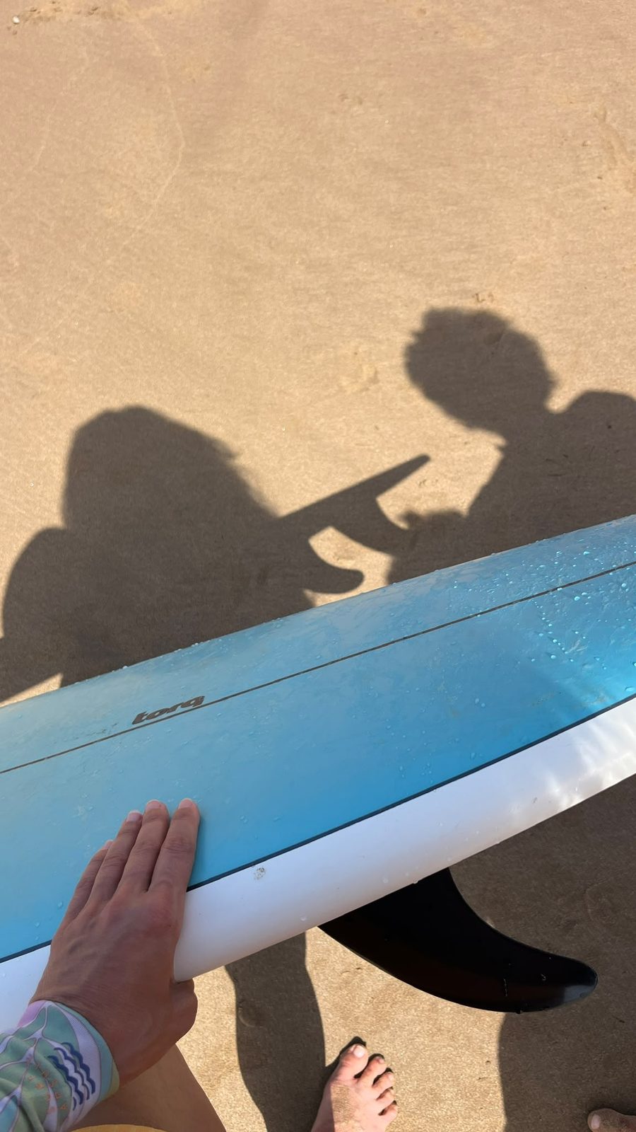 Shadows of coach and student beside a board on the sand