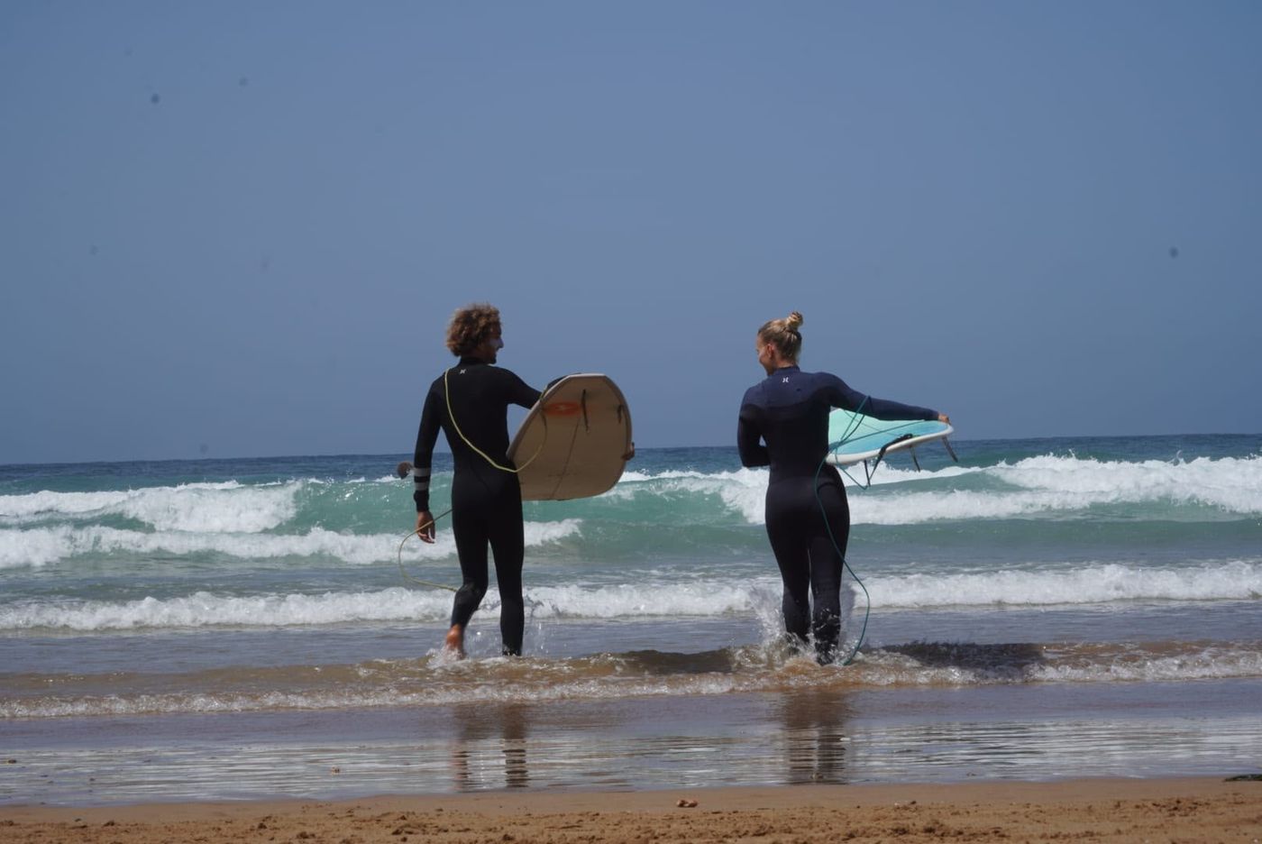 Surfers walking into the water with their boards